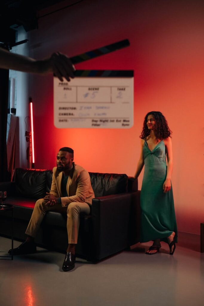 Two actors on a film set with dramatic lighting and a clapboard.